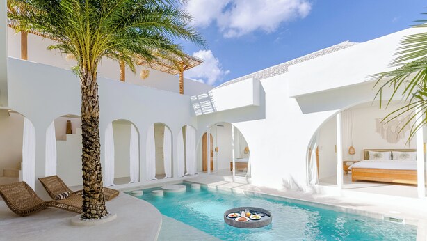 A pool area with lounge chairs, a palm tree, and a circular hot tub. - Villa Nokanhui by Pertama Stay (Canggu)
