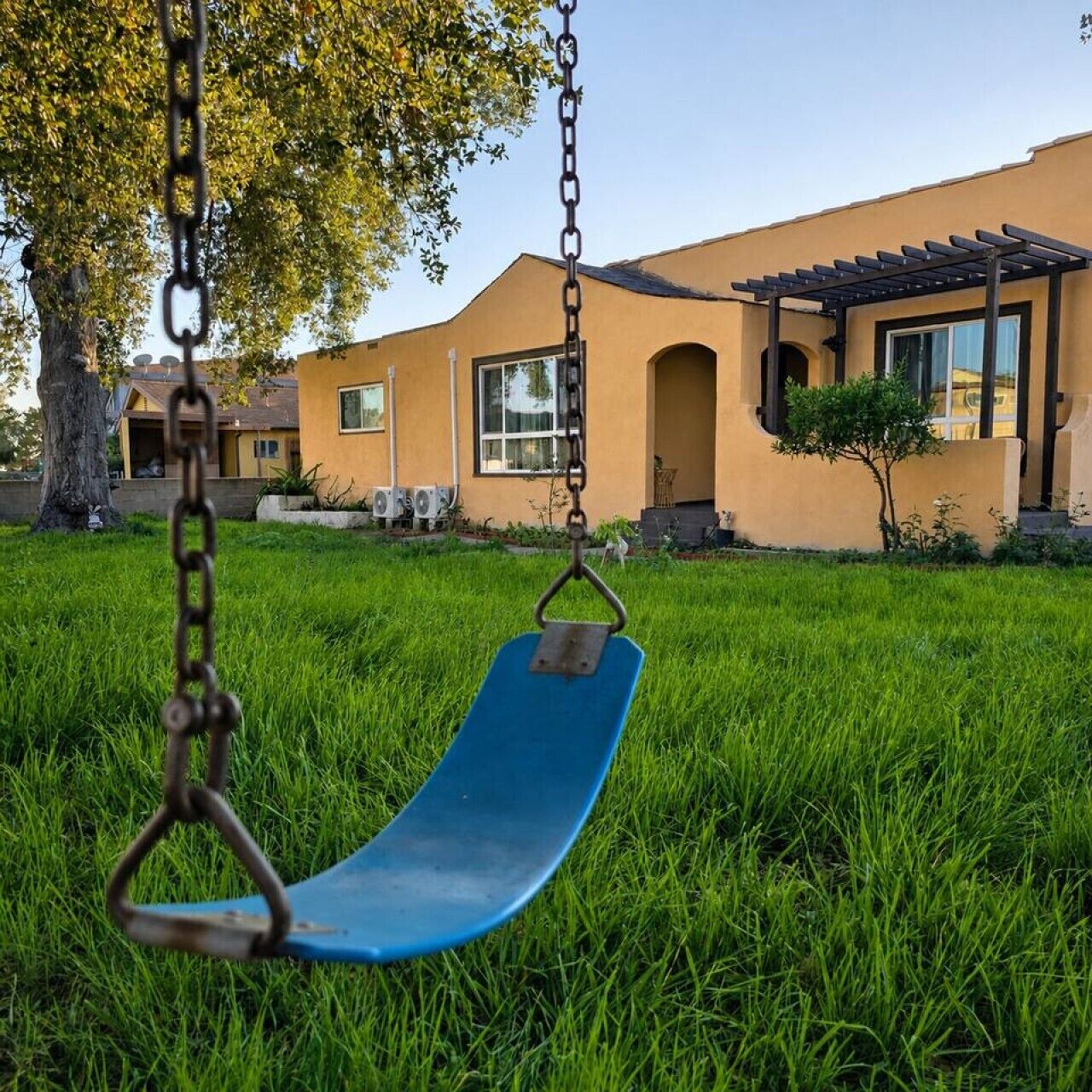 A swing set in a grassy area with a building in the background.