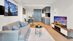 Ein modernes Wohnzimmer mit grauem Sofa, einem Couchtisch und einem Flachbildfernseher.
