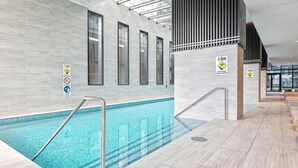Ein Hallenbad mit Sicherheitszeichen, gefliestem Boden und modernem architektonischen Design.