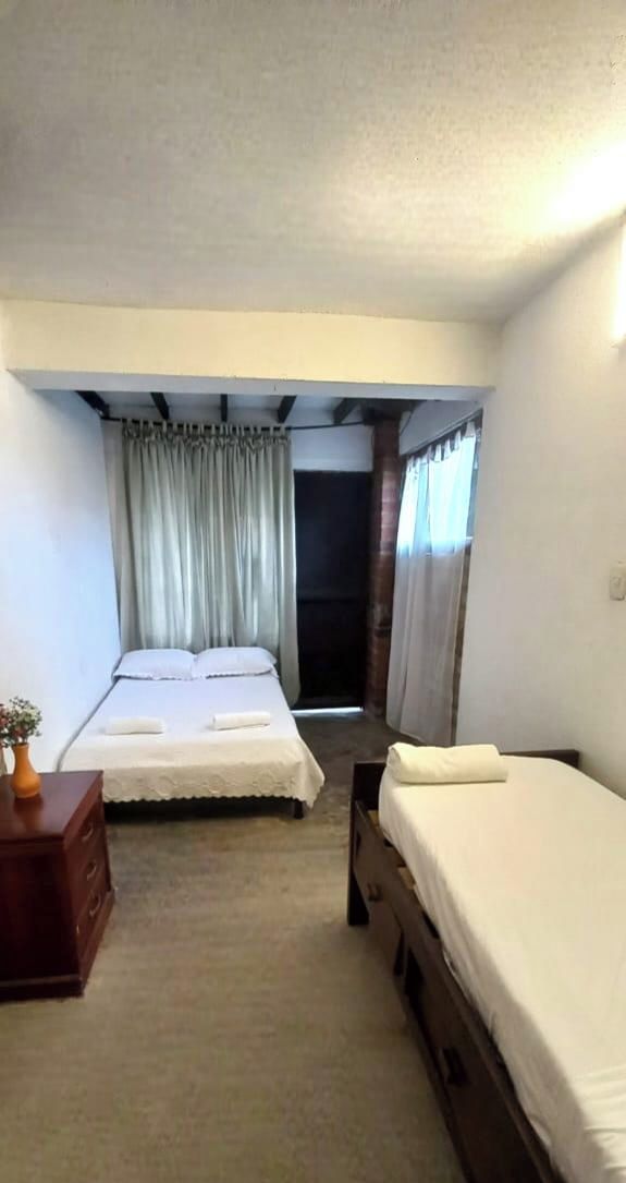 A hotel room with two beds, a wooden dresser, and a small table with a vase.
