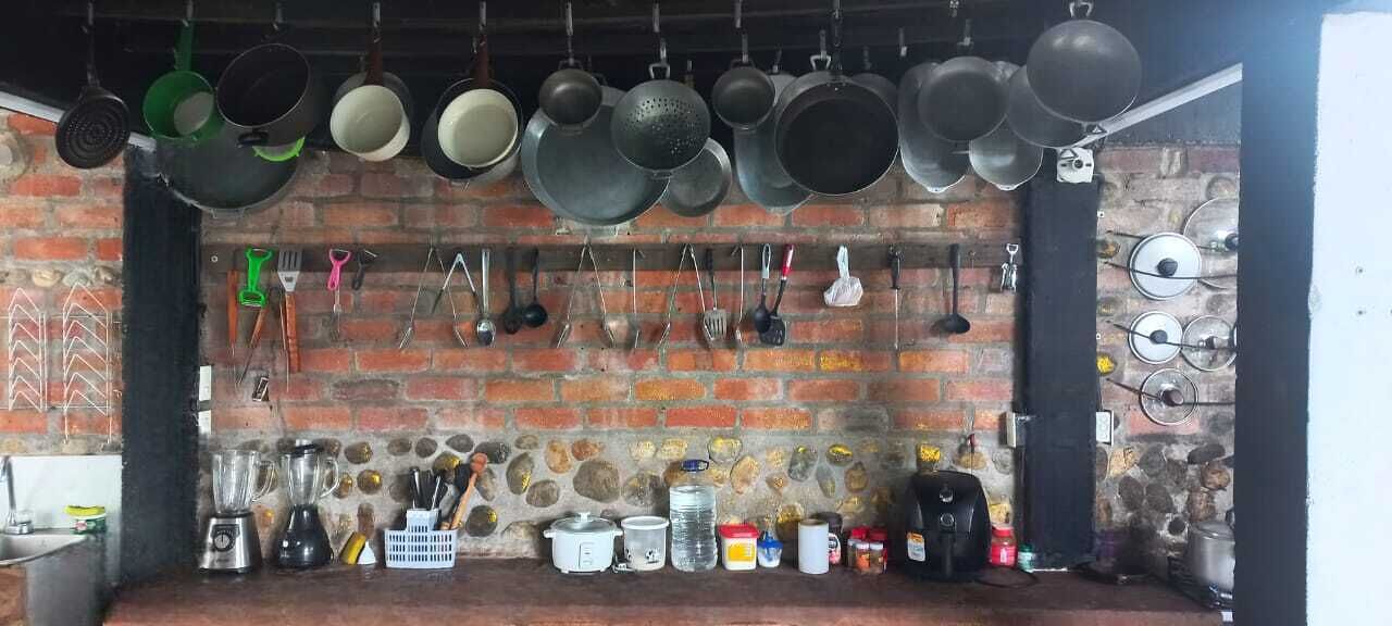 A kitchen with hanging pots and pans, a brick wall, and various kitchen utensils and appliances.