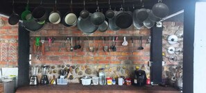A kitchen with hanging pots and pans, a brick wall, and various kitchen utensils and appliances. - Villa Tikuna (San Sebastian de Mariquita)
