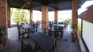 An outdoor patio area with brick pillars, wooden tables and benches, and potted plants. - Villa Tikuna (San Sebastian de Mariquita)