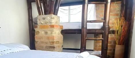 Una habitación con una cama, un pilar de piedra y una escalera de madera.