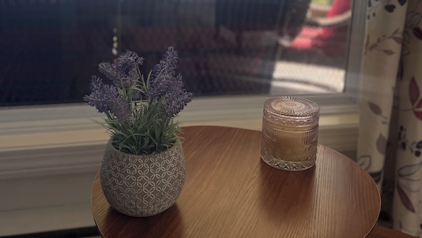 A small wooden table with a decorative vase and a glass candle.