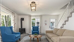 A living room with a blue armchair, beige sofa, and a round coffee table.
