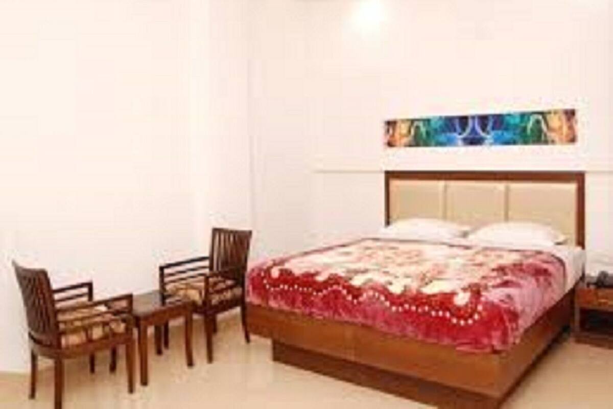 Ein Schlafzimmer mit einem Holzbett, einem Schreibtisch mit Stühlen und einem Bild an der Wand.