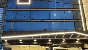 Ένα σύγχρονο κτιριακό συγκρότημα ξενοδοχείου με μια εντυπωσιακή, φωτεινή επιγραφή που αναγράφει: «Hotel Mahalinn».