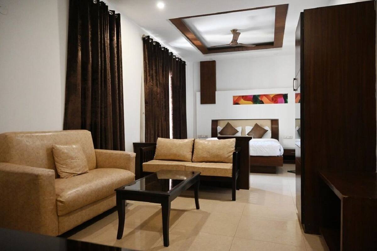 Ein Hotelzimmer mit einer Couch, einem kleinen Sofa, einem Couchtisch, einem Bett mit Kopfteil und einem Deckenventilator.