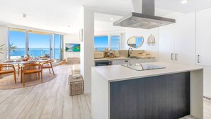 A modern kitchen with a central island, large windows offering a view of the sea, and a dining area with a view of the ocean.