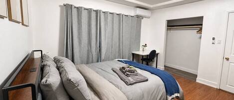 A bedroom with a bed, a desk, and a chair.