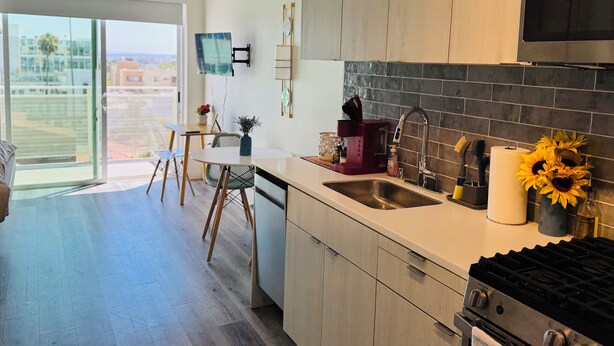 Cozinha moderna com uma grande janela, área de refeições e vista para a cidade.