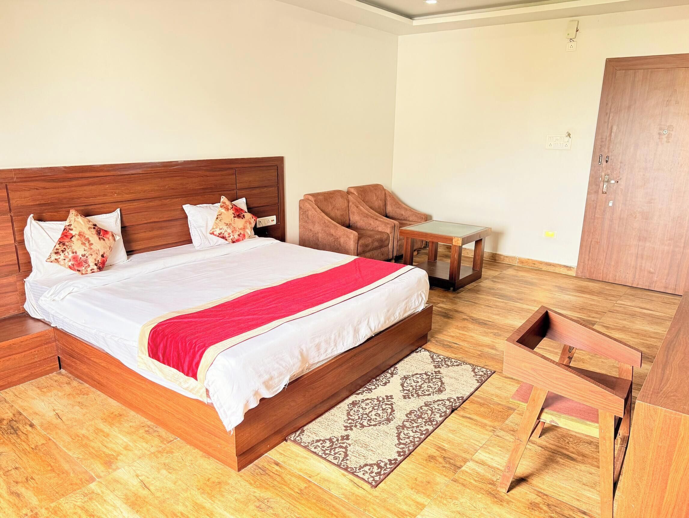 A neatly arranged bedroom with a wooden bed, a small table, a chair, and a wardrobe.
