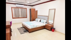 A modern bedroom with a wooden bed, a large mirror, and a desk with a chair. - PARADISE PREMIUM (Bhubaneshwar)