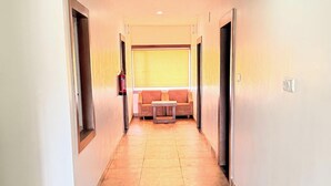 A hallway with a sofa and a table at the end, leading to a room. - PARADISE PREMIUM (Bhubaneshwar)