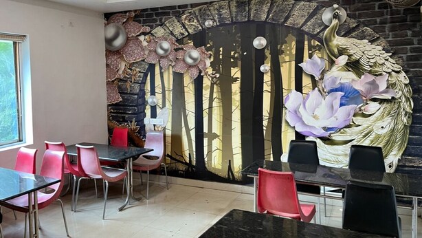 A dining area with a mural, red and black chairs, and a black table. - PARADISE PREMIUM (Bhubaneshwar)