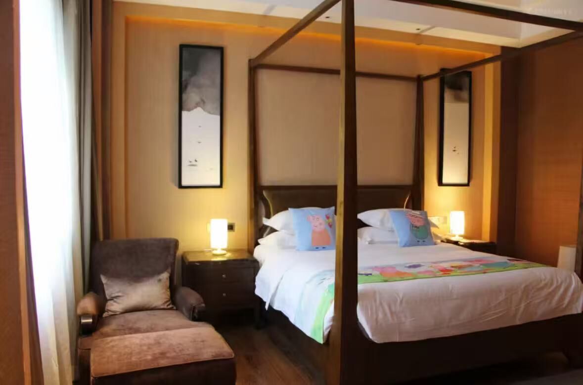 Camera d'hotel con un letto a baldacchino, una poltrona, un comodino e un quadro appeso al muro.