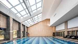 Una piscina interior con tragaluces, paredes de madera y zonas de estar.