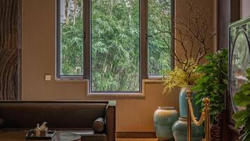 A room with a large window, a sofa, and a table.