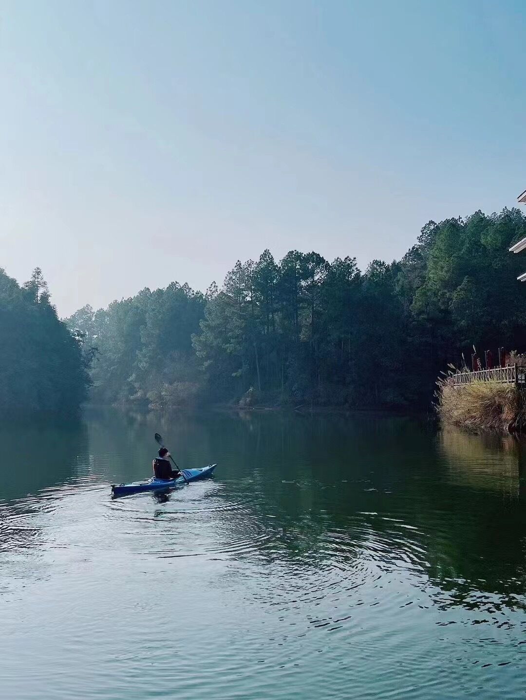 A calm river with a person kayaking.