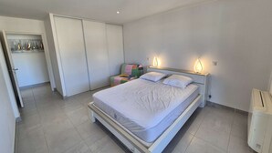 A bedroom with a bed, bedside tables, a wardrobe, and a radiator.