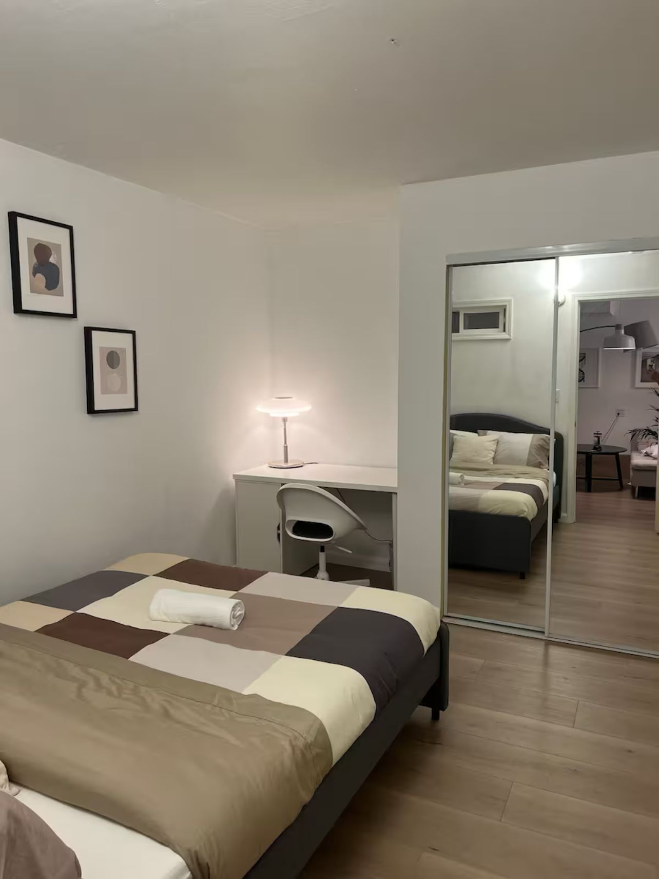 Una habitación de hotel con cama, escritorio, silla, lámpara y espejo.
