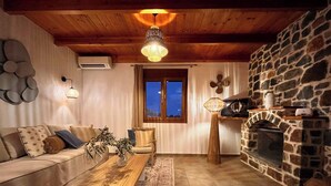 Un salon chaleureux avec une cheminée en pierre, un plafond en bois et un canapé agrémenté de coussins.