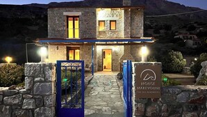 Une maison en pierre avec une façade en pierre, une porte en bois et une enseigne sur laquelle on peut lire : « MAISON MAREVOUNI, LA MER SE SOUVIENT ».