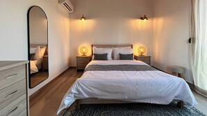 Une chambre à coucher avec un lit, des tables de chevet, un miroir et un ventilateur de plafond.