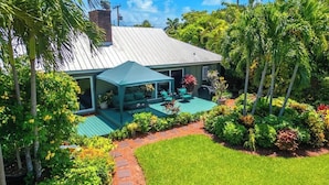 A house with a covered patio, a lawn, and tropical vegetation. - Swarovski Sanctuary (Key West)