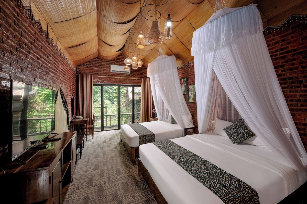 A room with two beds, a TV, and a balcony.