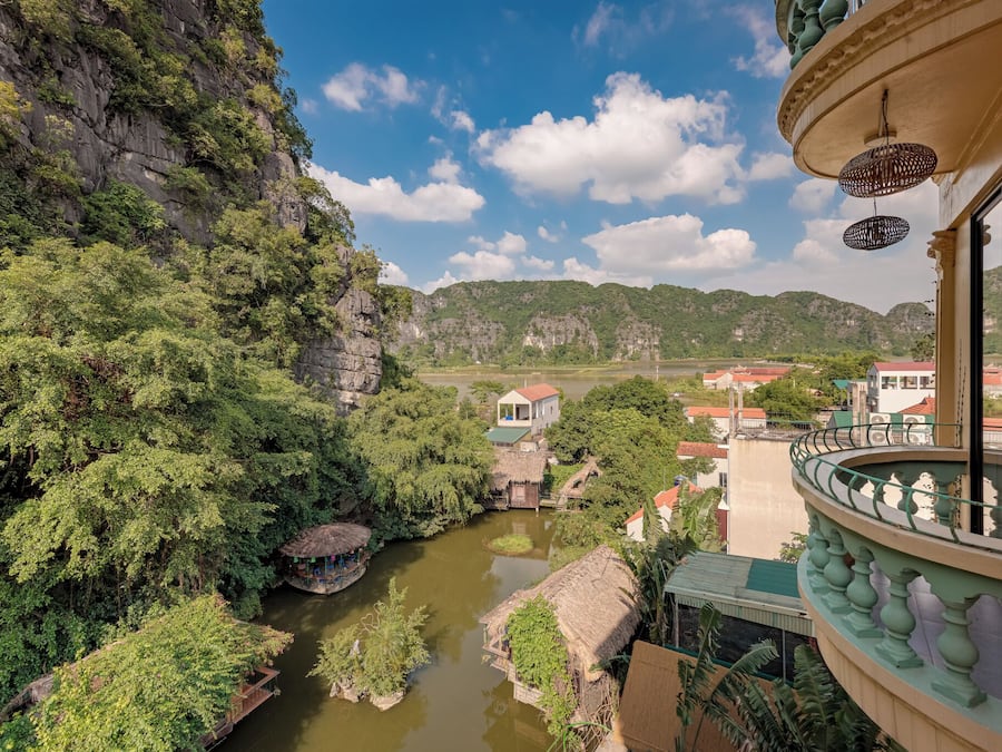 Um rio com uma casa à direita e uma varanda com grades.