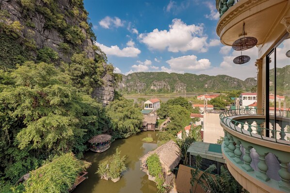 A river with a house on the right and a balcony with a railing. - Emerald Retreat Tam Coc (Nam Hoa Lu)