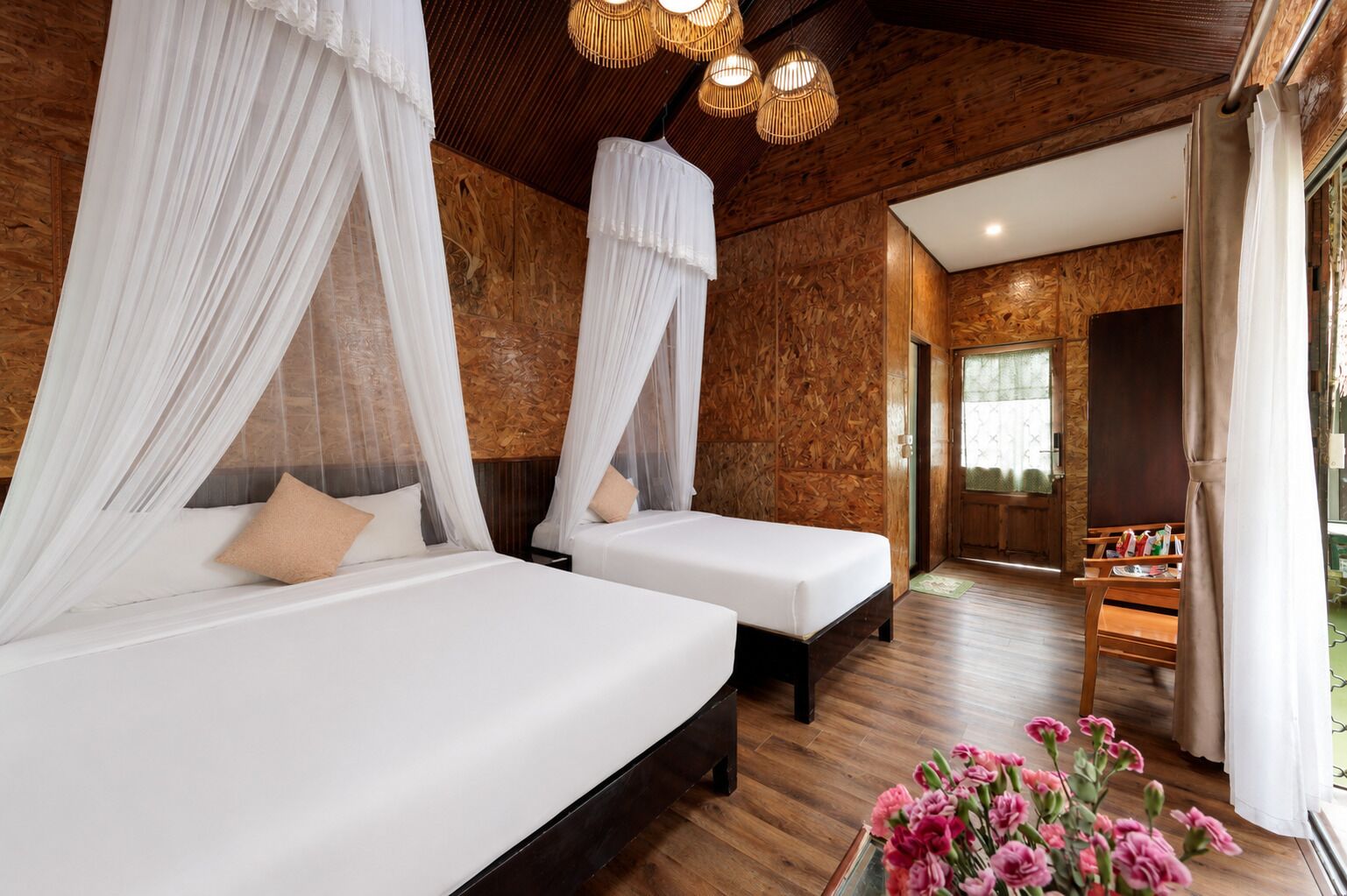 Ein Zimmer mit zwei Betten, jeweils mit Baldachin, Holzwänden und Holzboden. Eine Bank und ein kleiner Tisch mit Gegenständen darauf.