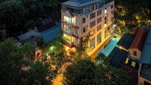 Un hotel de varios pisos con piscina, rodeado de exuberante vegetación y montañas.