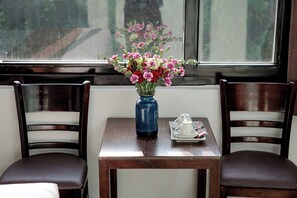 Ein Tisch mit einer Blumenvase, einer Tablett mit Tassen und einem Teekessel sowie zwei Stühle.