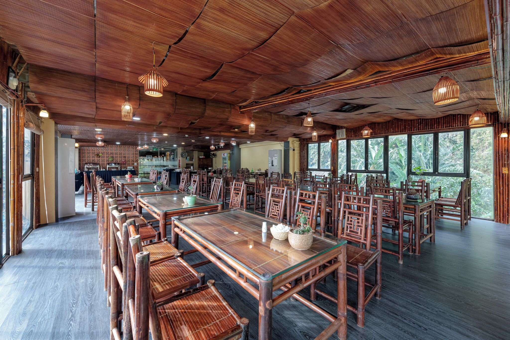 A spacious dining area with bamboo furniture and large windows offering a view of the outdoors.