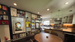 A modern kitchen with built-in shelves, a dining area with a round table, and a view of the outdoors.