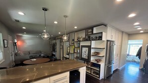 A modern kitchen with a central island, built-in shelves, and a refrigerator.