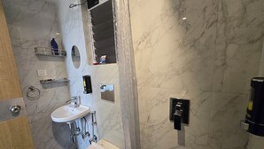 A bathroom with a sink, mirror, towel rack, and a shower area.