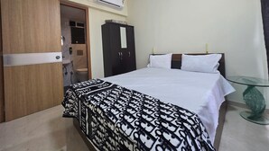 A hotel room with a bed, wardrobe, and an air conditioning unit.