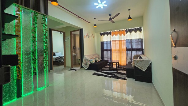 A modern living room with a glass partition, ceiling fans, and a dining area with a table and chairs.