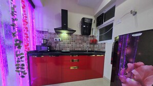 A kitchen with red cabinets, a black range hood, a microwave, and a water dispenser.