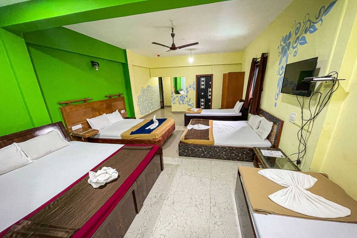 A hotel room with two beds, a TV, and a ceiling fan.