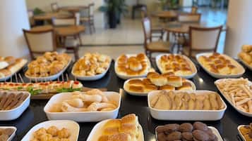 Um buffet com diversos pães e doces.