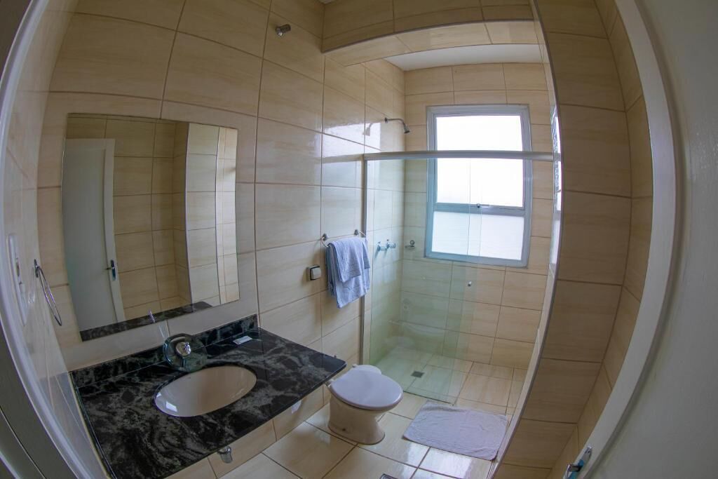 Un baño con lavamanos de mármol, inodoro, cabina de ducha de vidrio y un espejo grande.