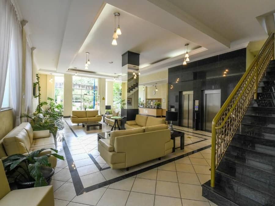 A spacious lobby with a sofa, chairs, and a staircase.