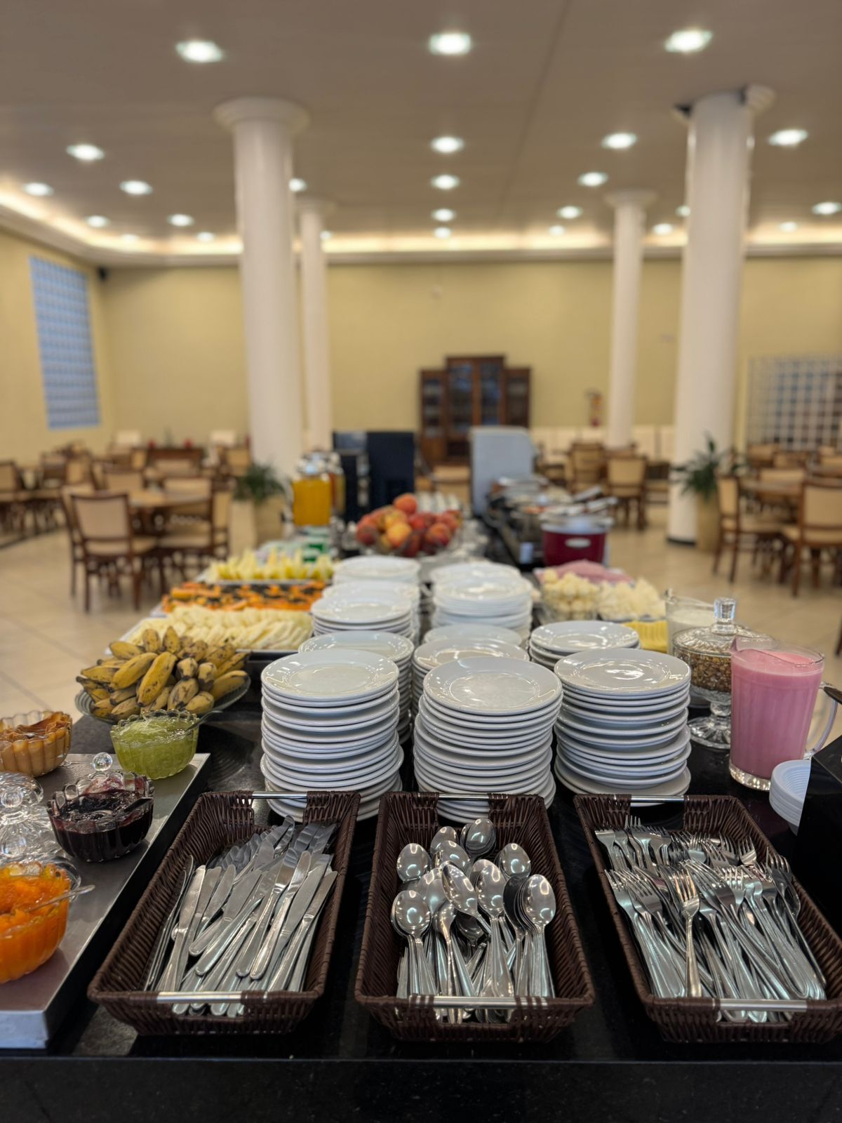 A buffet setup with plates, bowls, and utensils.