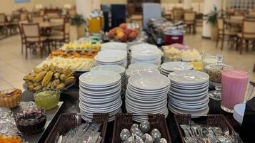 A buffet setup with plates, bowls, and utensils.